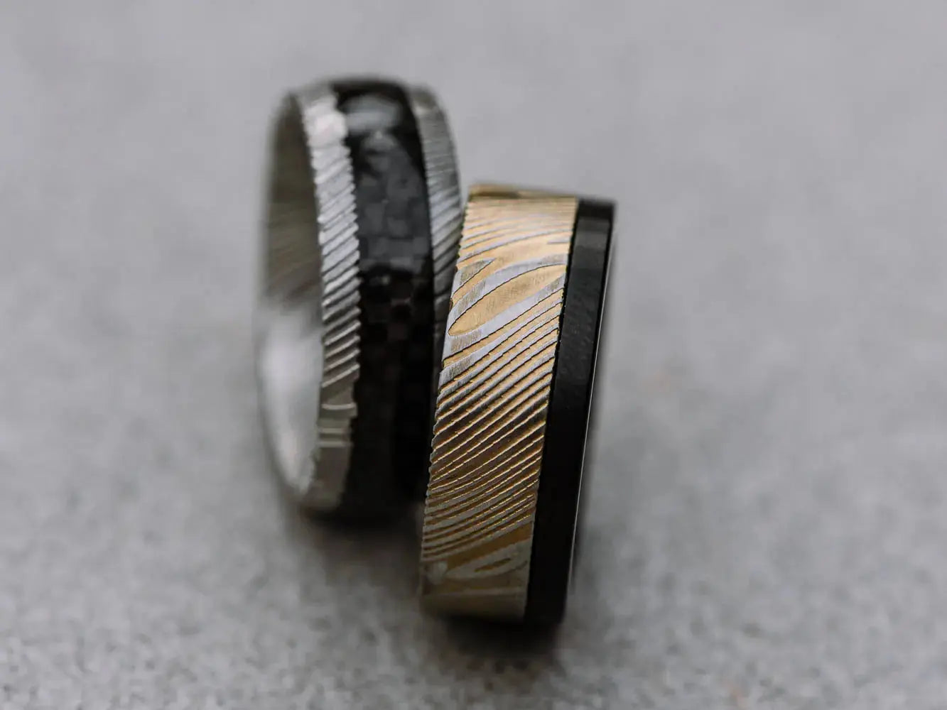 two damascus steel rings silver and black stripe inlay and black with gold outer half