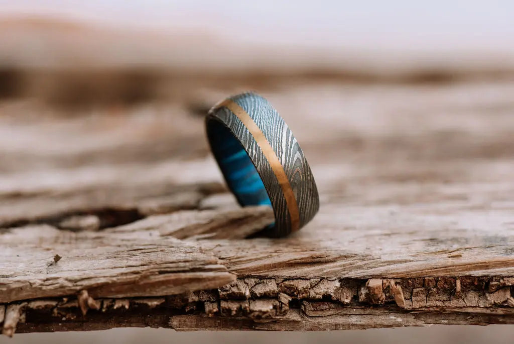 Damascus Steel Ring With Gold Inlay on Wooden Backdrop