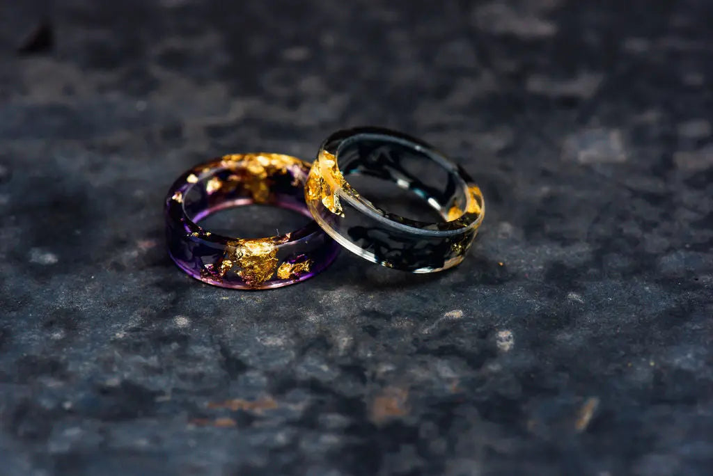 Two Transparent Resin Rings with Gold Accents on Charcoal Backdrop