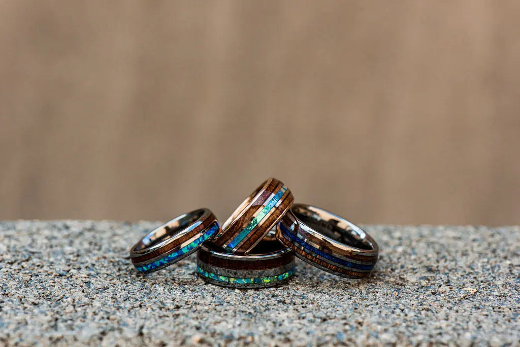 Four Tungsten Rings Laying on One Another with a Wood and Marble Backdrop