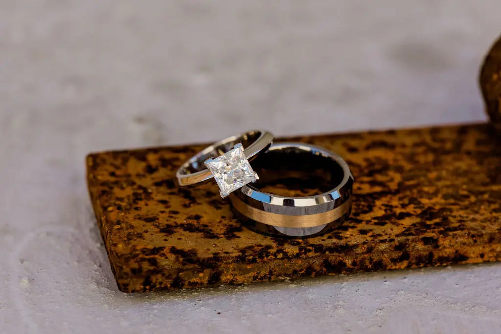 One Tungsten and One Moissanite Wedding Ring Laying On a Rustic Plate