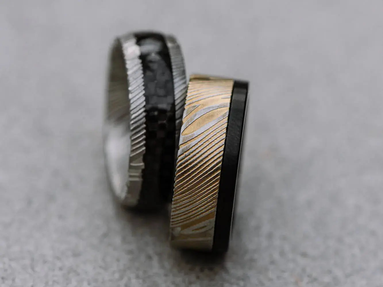 two damascus steel rings silver and black stripe inlay and black with gold outer half 